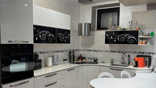 A modern kitchen with white cabinets, a black and white backsplash, a stainless steel range hood, and a round dining table with chairs. - House with private pool x families and companies (Caprino veronese)