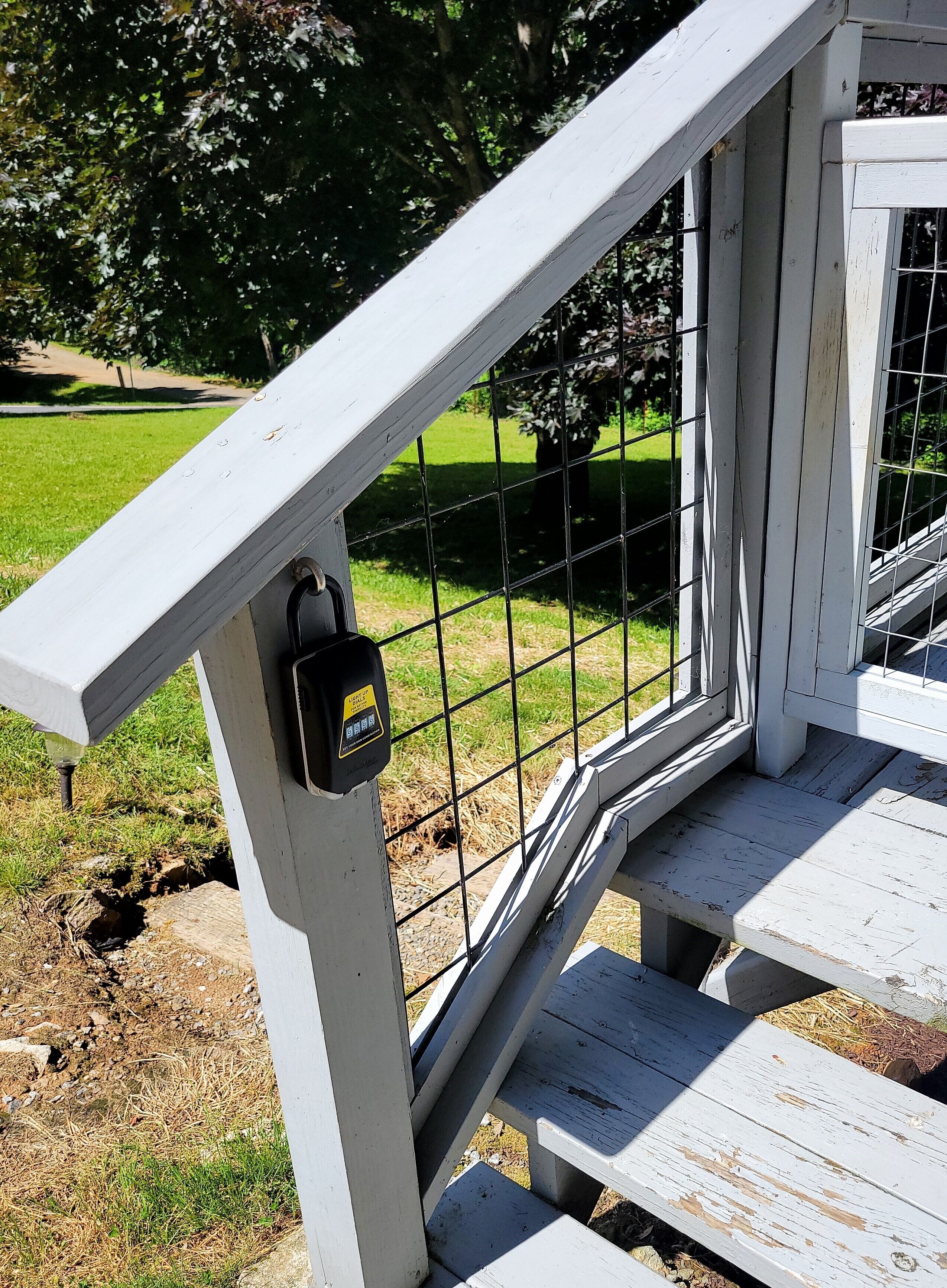 Un escalier en bois peint en blanc, doté d’une rampe en métal et d’un clavier de sécurité.