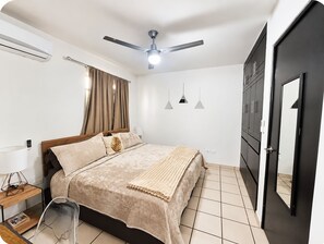 A bedroom with a bed, a ceiling fan, a wardrobe, and a door.