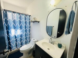 A bathroom with a toilet, sink, mirror, and blue patterned shower curtain. - Charming Condo - Walk to the Beach, Dinning & Nightlife (Cabo San Lucas)