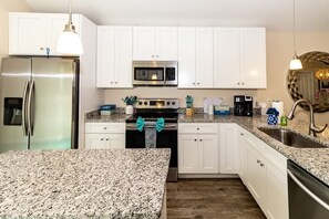 Fully equipped kitchen with stainless steel appliances, granite countertops, and a sink with a faucet.