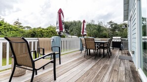 Um deck de madeira com móveis de exterior e churrasqueira.