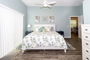 A bedroom with a bed, a nightstand, a dresser, a ceiling fan, and artwork on the wall. - Beach Haven (saint augustine)