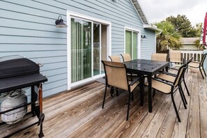 A covered patio area with a grill, dining table, and chairs. - Beach Haven (saint augustine)