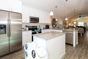A modern kitchen with stainless steel appliances, a granite countertop island, and a dining area with a sofa and table. - Beach Haven (saint augustine)