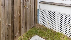 A wooden fence, a white lattice fence, and a concrete pathway in a residential setting. - Beach Haven (saint augustine)