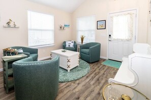 Una habitación con sillas color aguamarina, una mesa de centro blanca y una puerta con un cortinero decorativo.