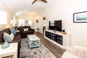 A living room with a sofa, coffee table, TV, and entertainment unit. - Beach Haven (saint augustine)