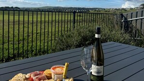 A table with a bottle of wine, a glass, and a charcuterie board with crackers and a jar of olives.