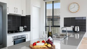 A modern kitchen with white cabinets, a stainless steel sink, and a large window.