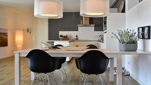 Une cuisine moderne avec des meubles blancs, un îlot central et des chaises noires.
