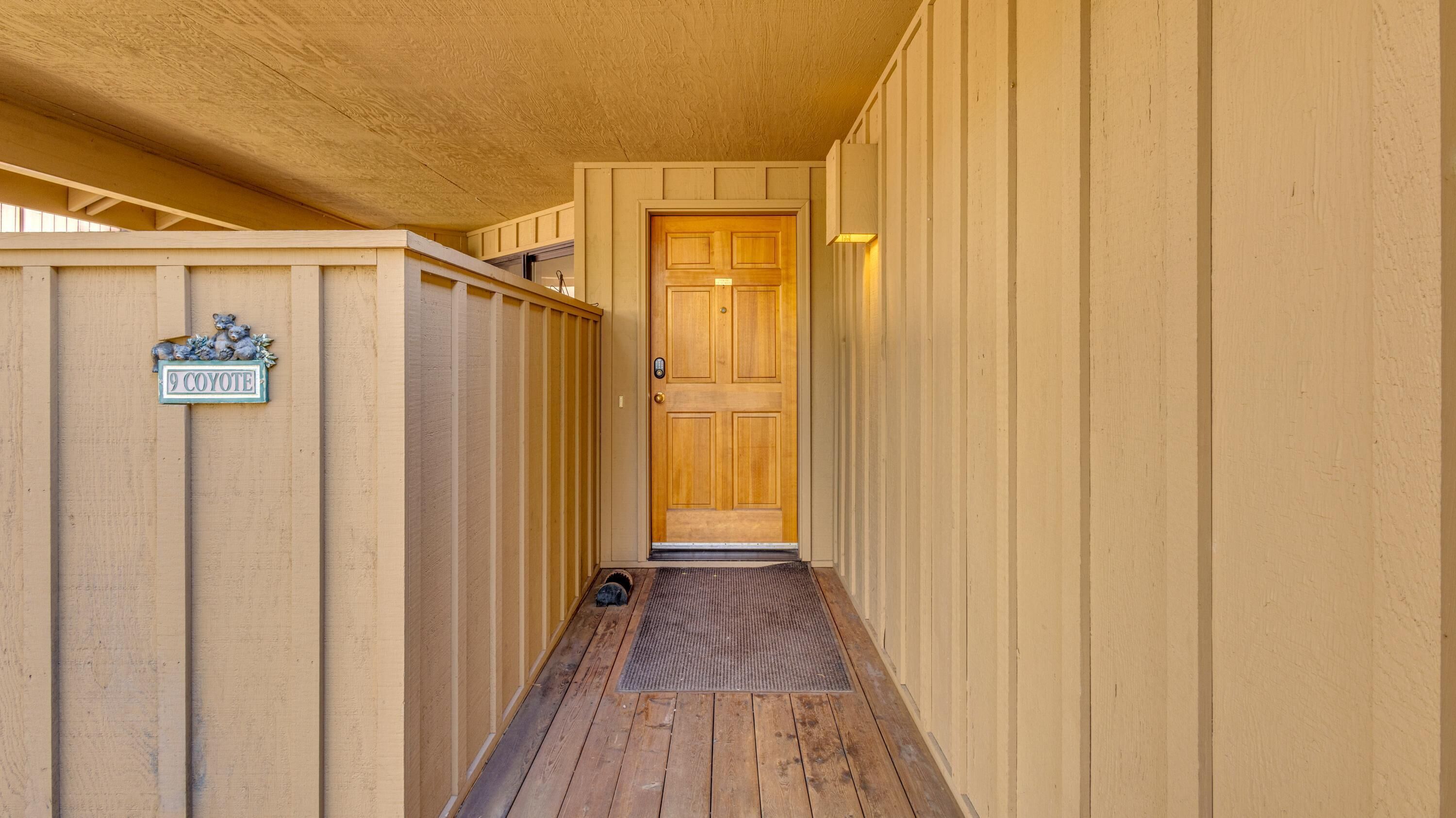 Un couloir extérieur en bois mène à une porte dotée d’une boîte aux lettres et d’une enseigne indiquant « 9 Coyote ».