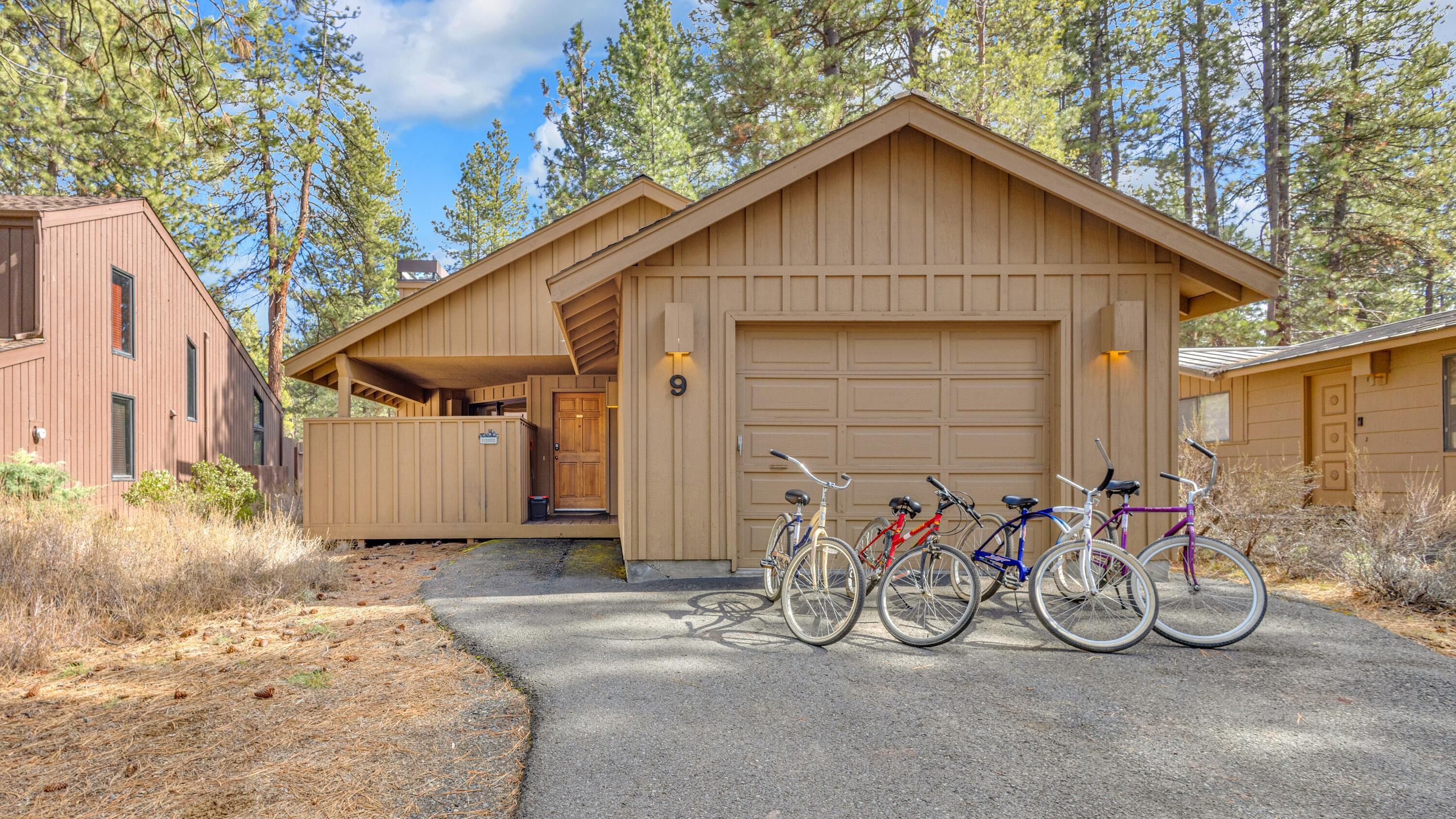A cabin with a garage, a covered porch, and bicycles parked in front.