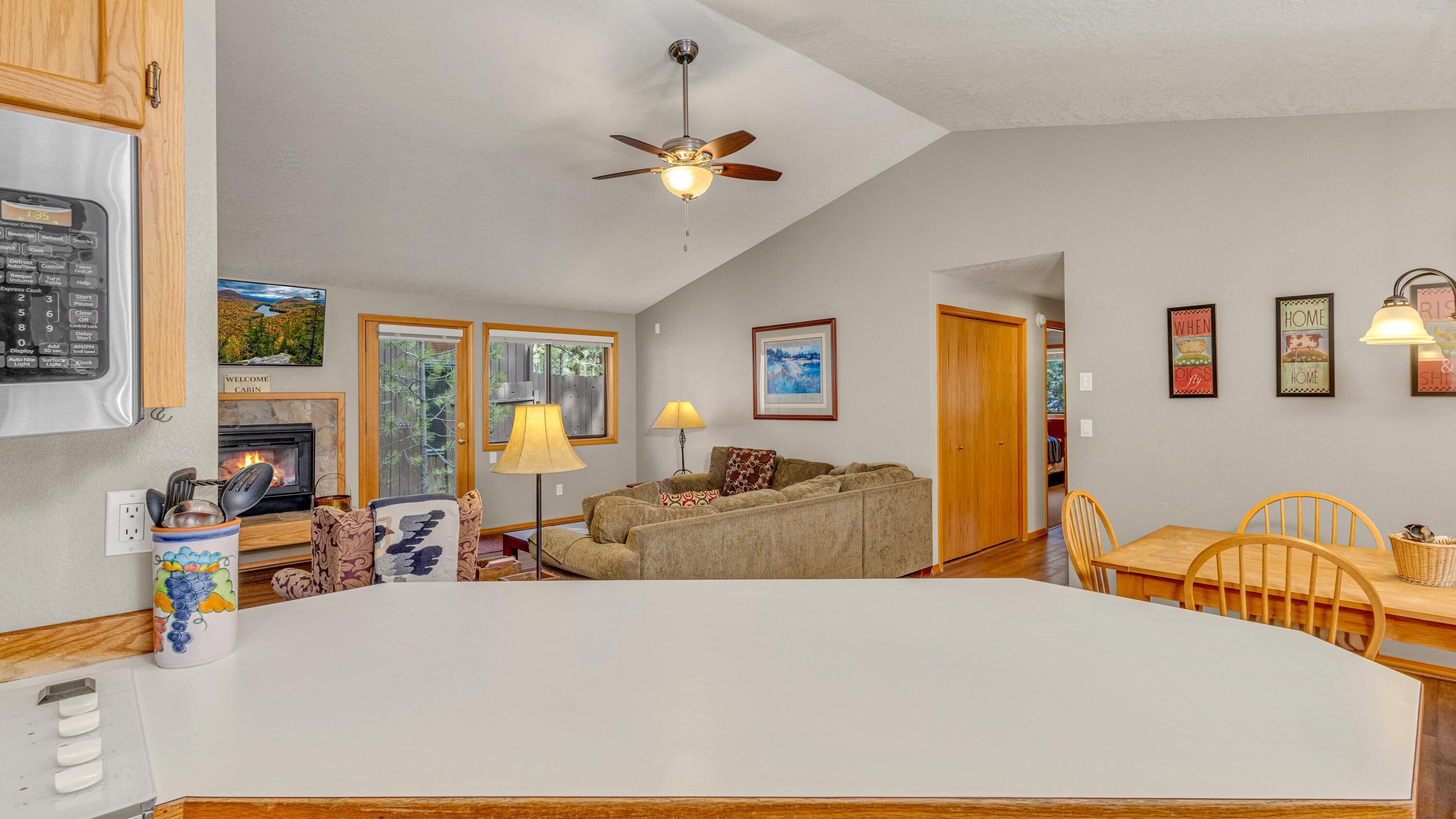 A spacious living area with a fireplace, a ceiling fan, and a dining table with chairs.