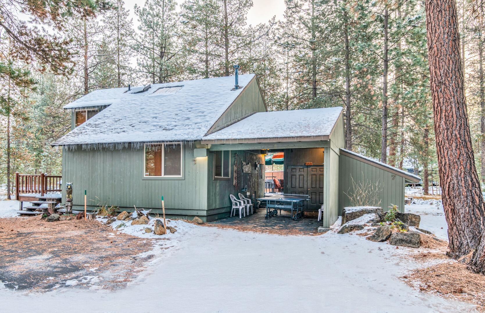 A cabin with a porch, a ping pong table, and a small deck.