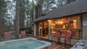 Un chalet confortable doté d’un bain à remous, d’une terrasse en bois et d’un espace extérieur aménagé, le tout entouré d’arbres.