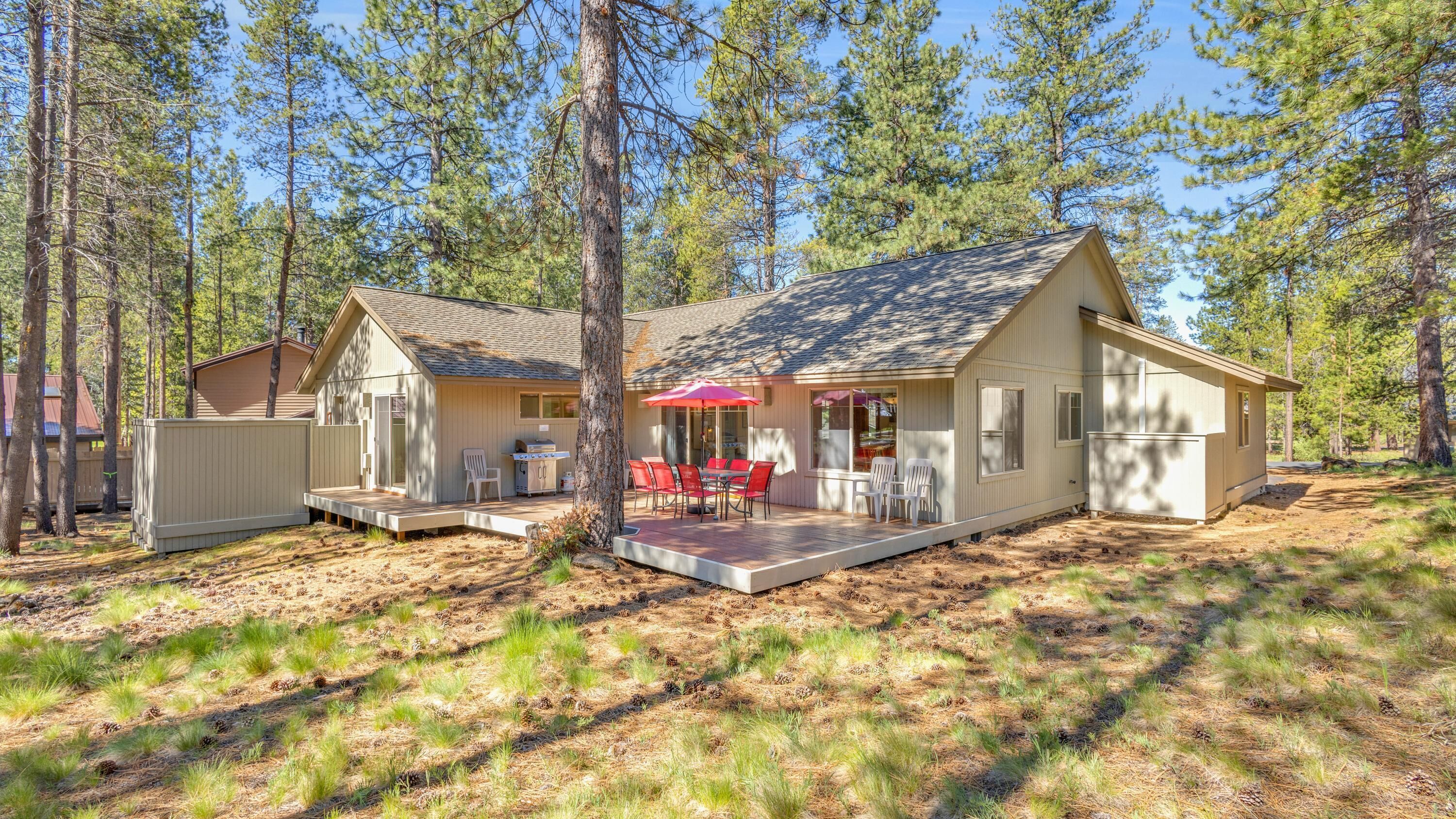 Una cabaña con terraza, mobiliario exterior y una pequeña cocina.