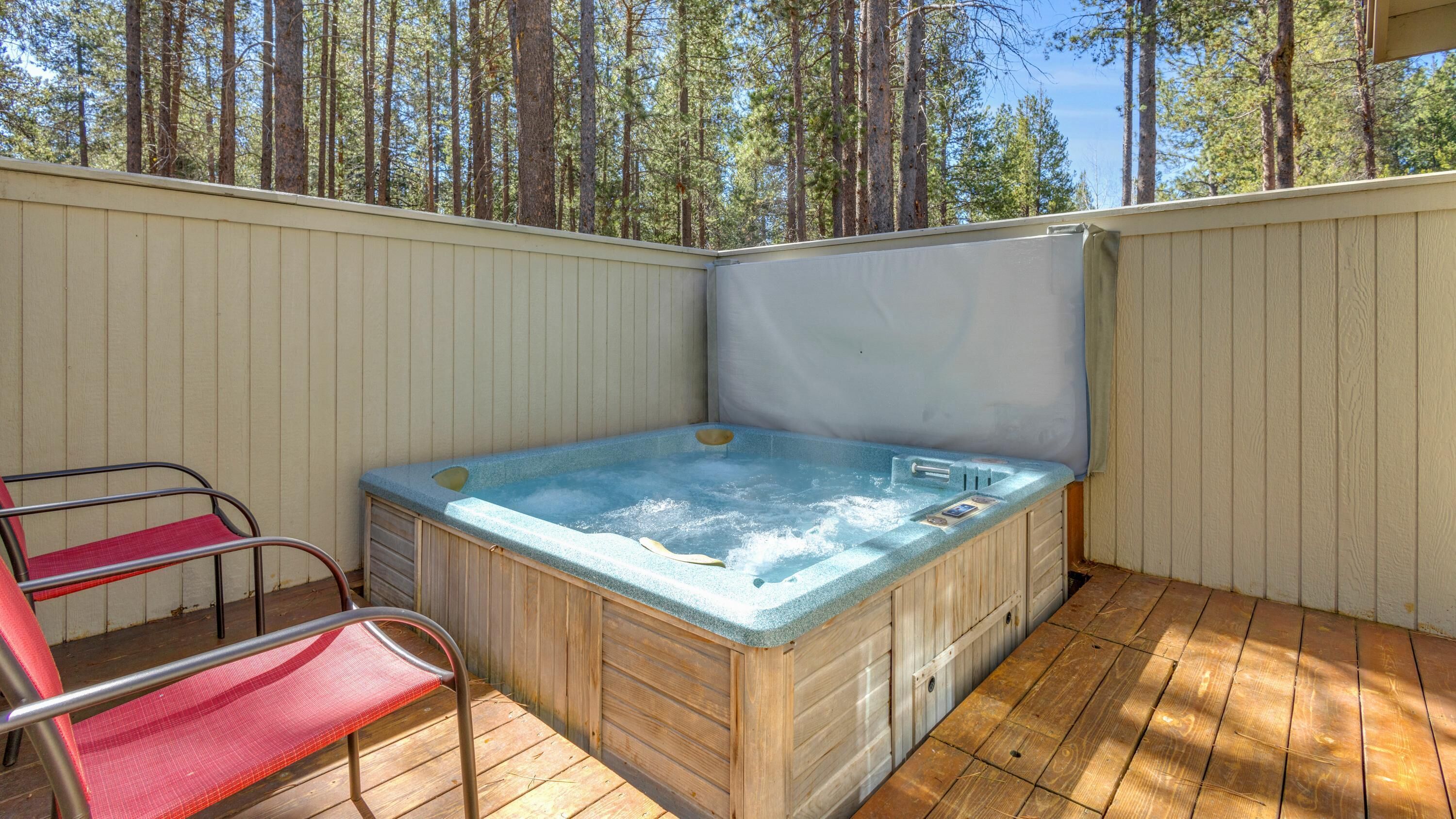 Un bain à remous avec une terrasse en bois et une chaise en métal.