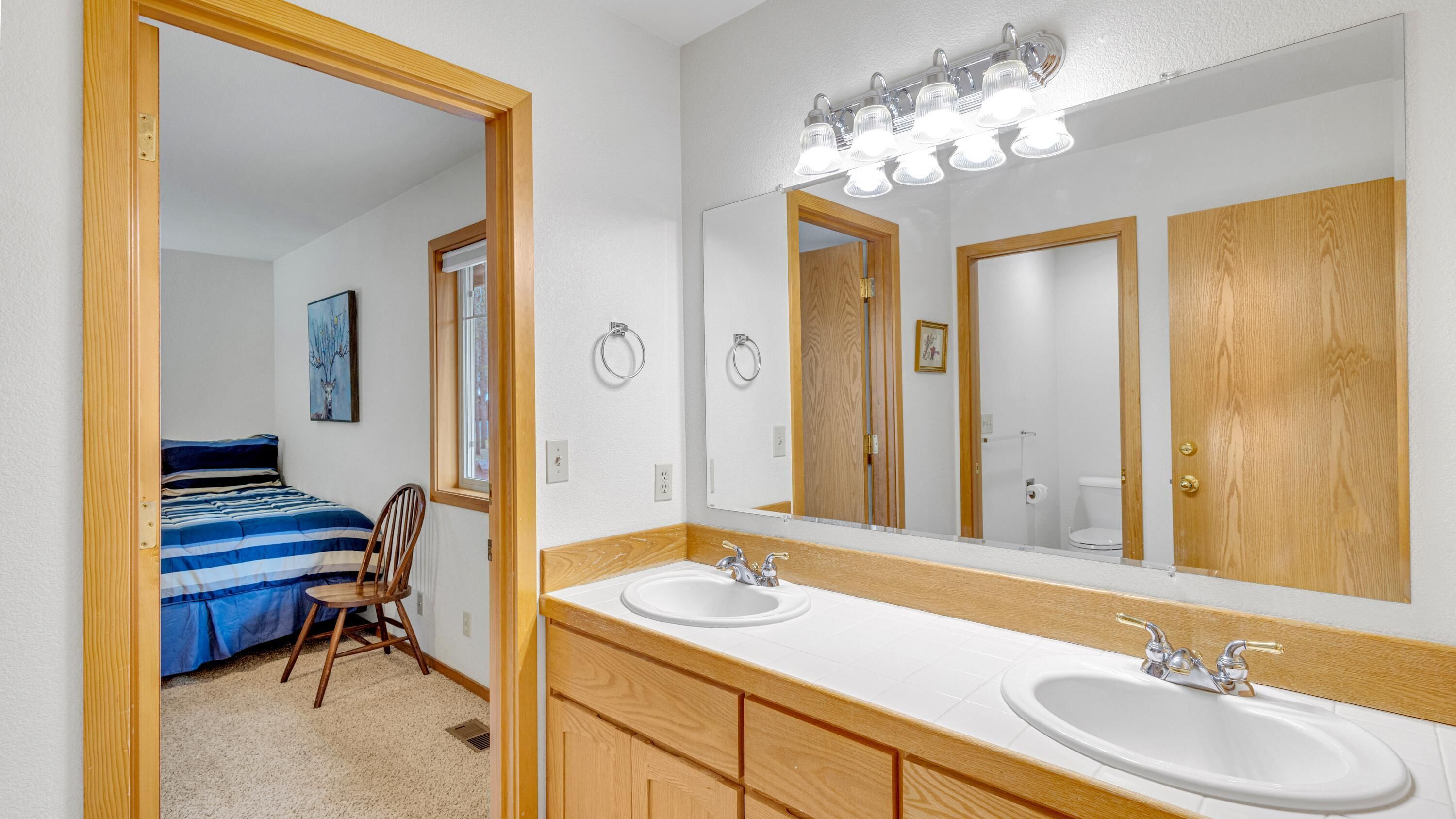 A bathroom with two sinks, a large mirror, and a wooden vanity.