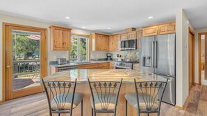 A spacious kitchen with wooden cabinets, a stainless steel refrigerator, a microwave, and a gas stove. - Awbrey Lane 2 (Bend)