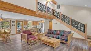 A spacious living area with a wooden staircase, a sofa, and a dining table. - Awbrey Lane 2 (Bend)