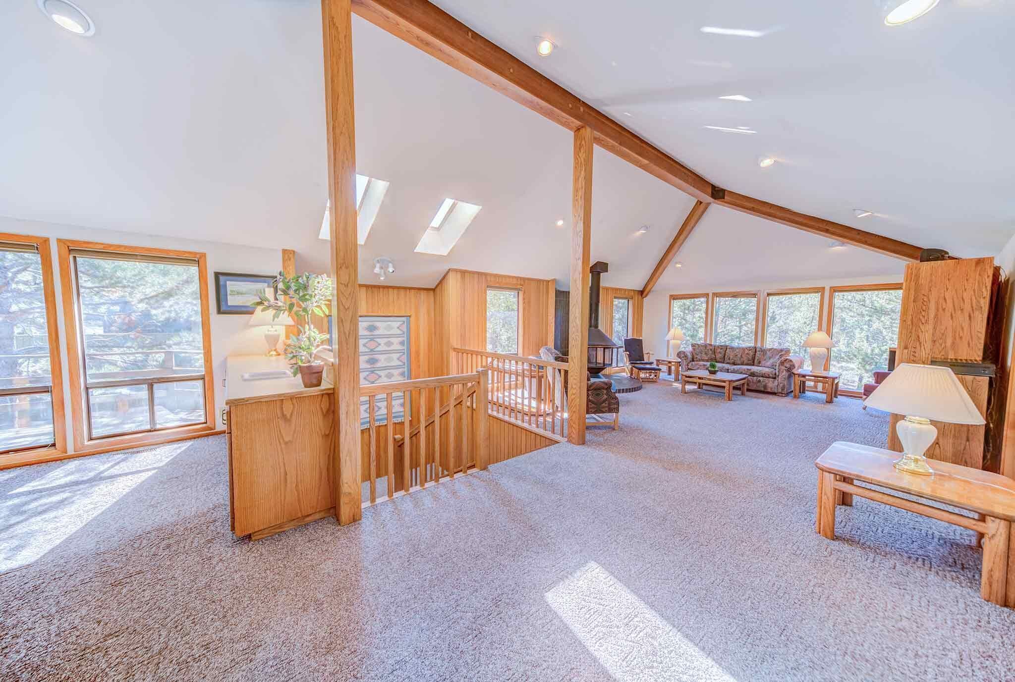 A spacious loft-style room with high ceilings, large windows, and a cozy seating area.