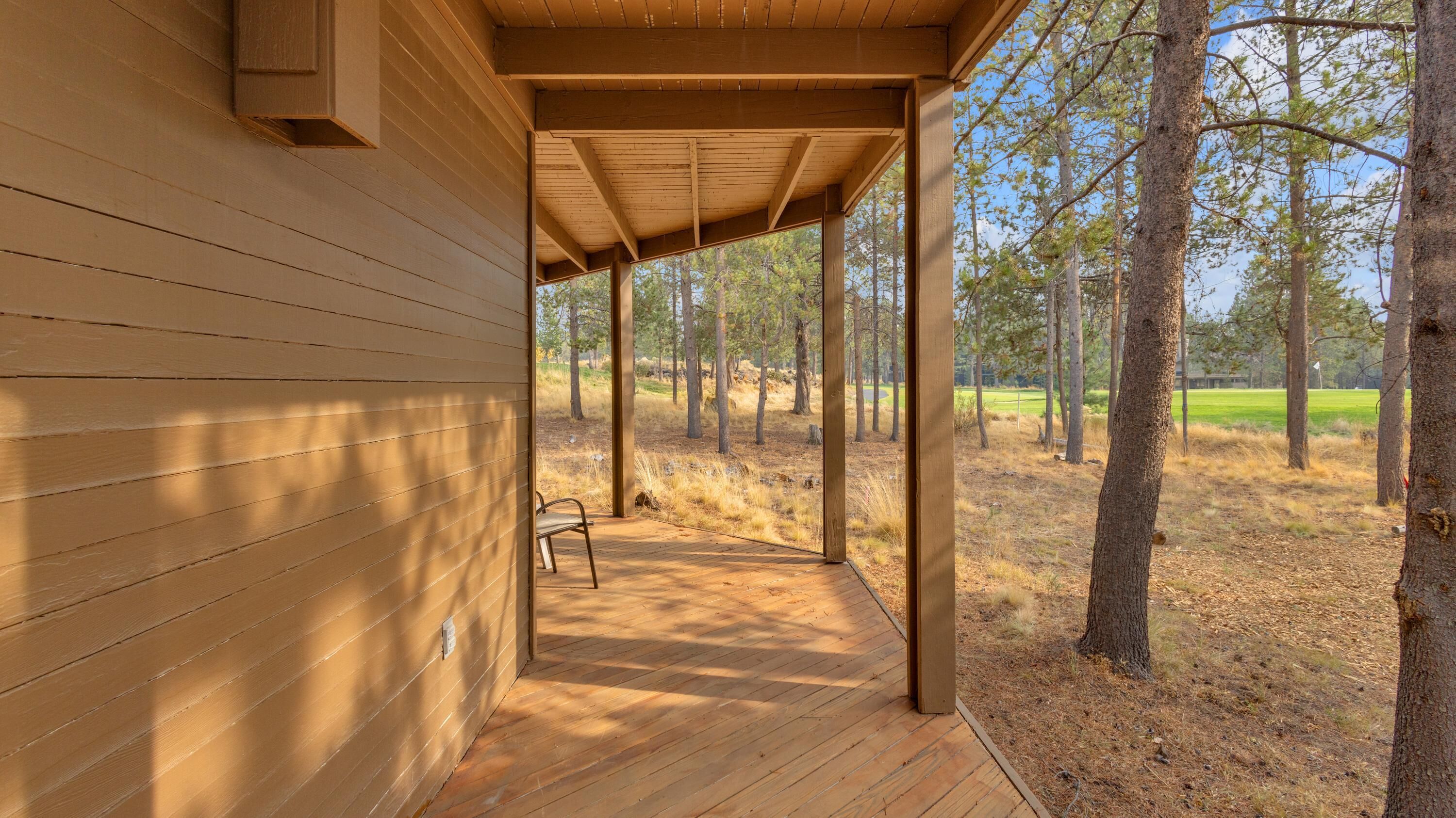 A wooden cabin with a covered porch and a bench.
