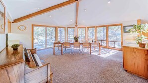 A spacious room with a large dining table, chairs, and a piano.