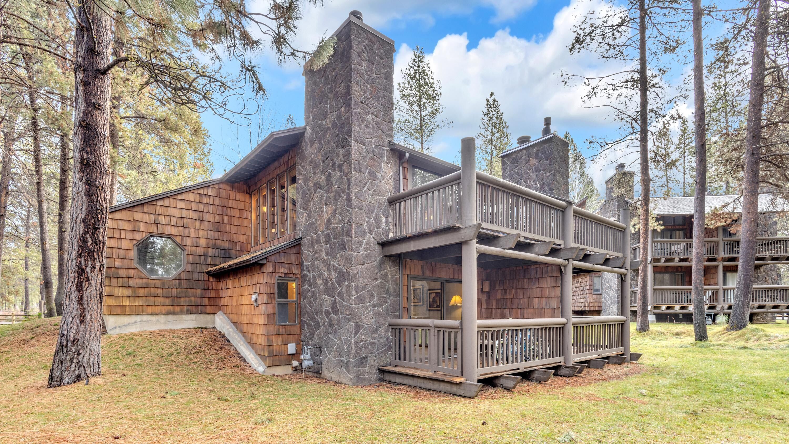 A log cabin-style building with a stone chimney, wooden deck, and multiple balconies.