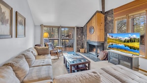 A cozy living room with a fireplace, a large TV, and a comfortable sofa. - Wildflower Condo 54 (Bend)