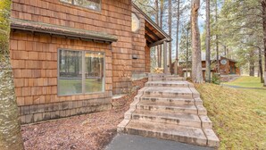 A wooden cabin with a stone staircase leading to the entrance, surrounded by trees. - Wildflower Condo 54 (Bend)