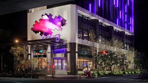 A modern hotel with a prominent neon sign, a 50 mph speed limit sign, and a covered entrance area.