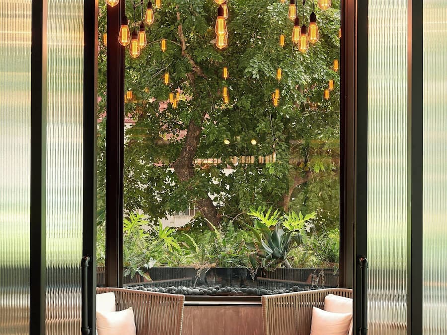 A modern interior with a glass partition, wicker furniture, and hanging light fixtures.