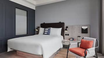 A modern bedroom with a large bed, bedside tables, a chair, and a wall-mounted light fixture.