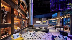 A modern lounge area with a check-in desk, seating arrangements, and a fire pit.