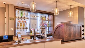 Un espace bar avec un assortiment de bouteilles d’alcool, une caisse enregistreuse et un terminal de paiement.