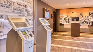 Un hall d’hôtel équipé de bornes en libre-service, d’un écran numérique et d’un grand mur orné de phrases inspirantes.