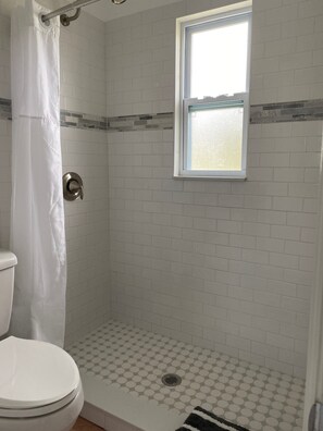 Chuveiro, toalhas de banho, sabonete, papel higiênico