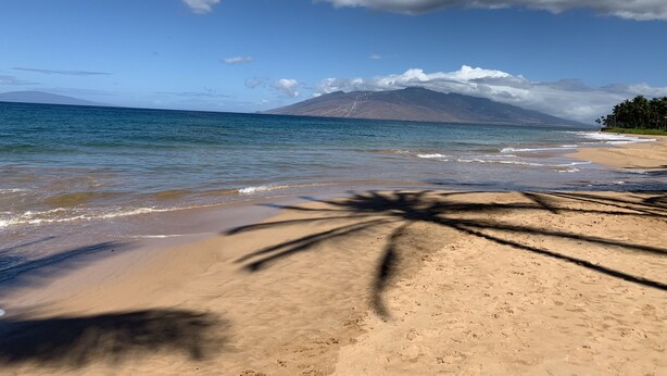 A beach with clear skies, waves, and a mountain in the distance. - Beautiful - Palms at Wailea 1802 (Kihei)