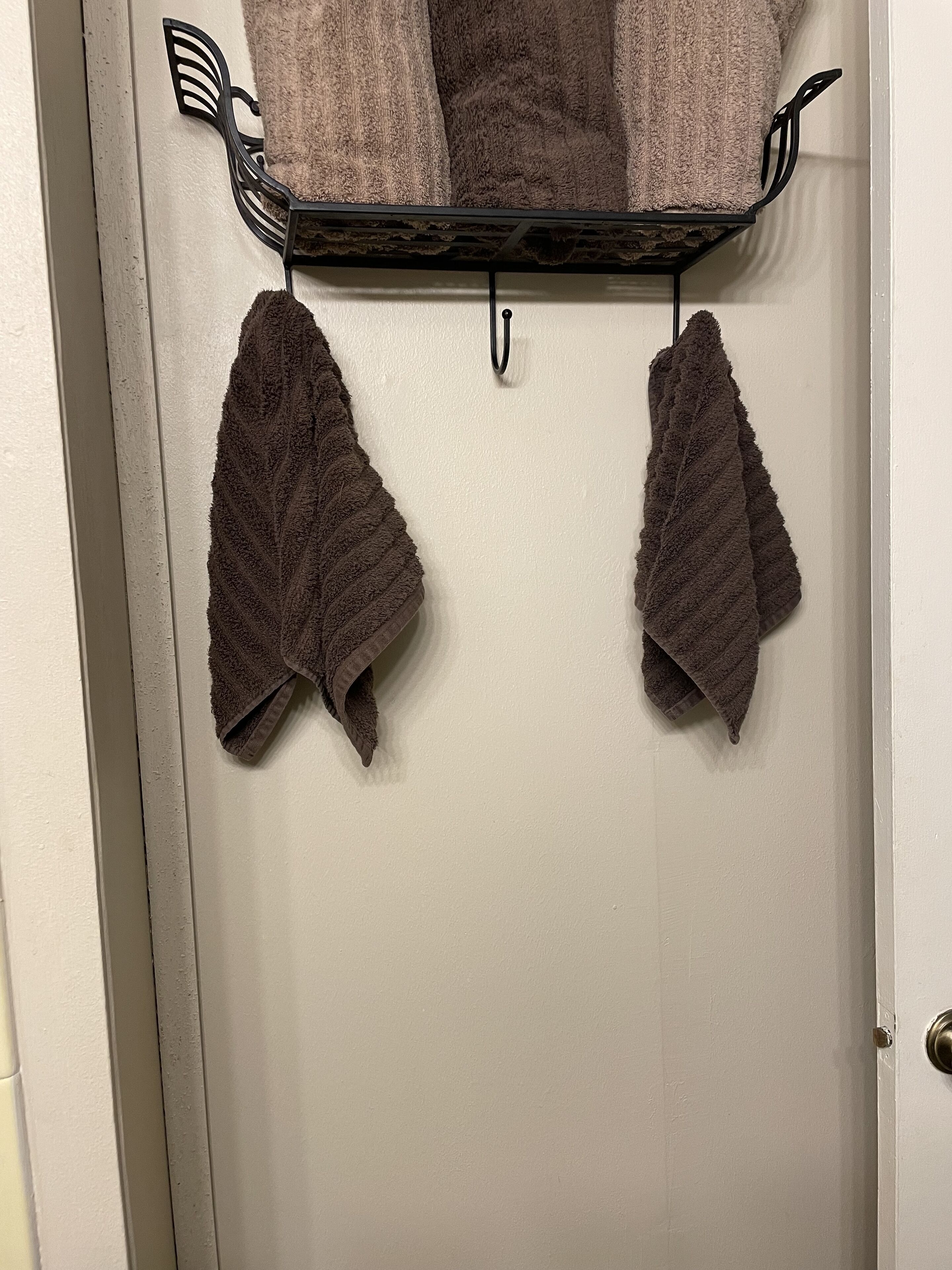 A white door with a towel rack holding two towels and a metal tray with a towel.