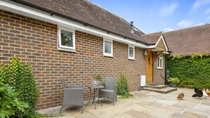 A brick house with a tiled patio, two wicker chairs, a small table, and a potted plant. - Chambers Place (Reading)