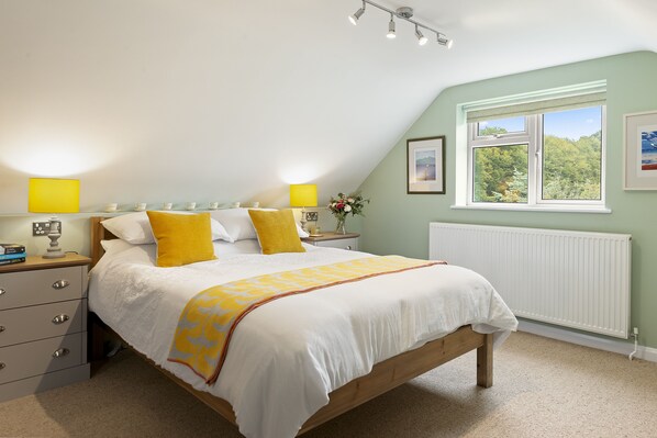 A bedroom with a bed, bedside tables, a window with a view, and a radiator. - Chambers Place (Reading)