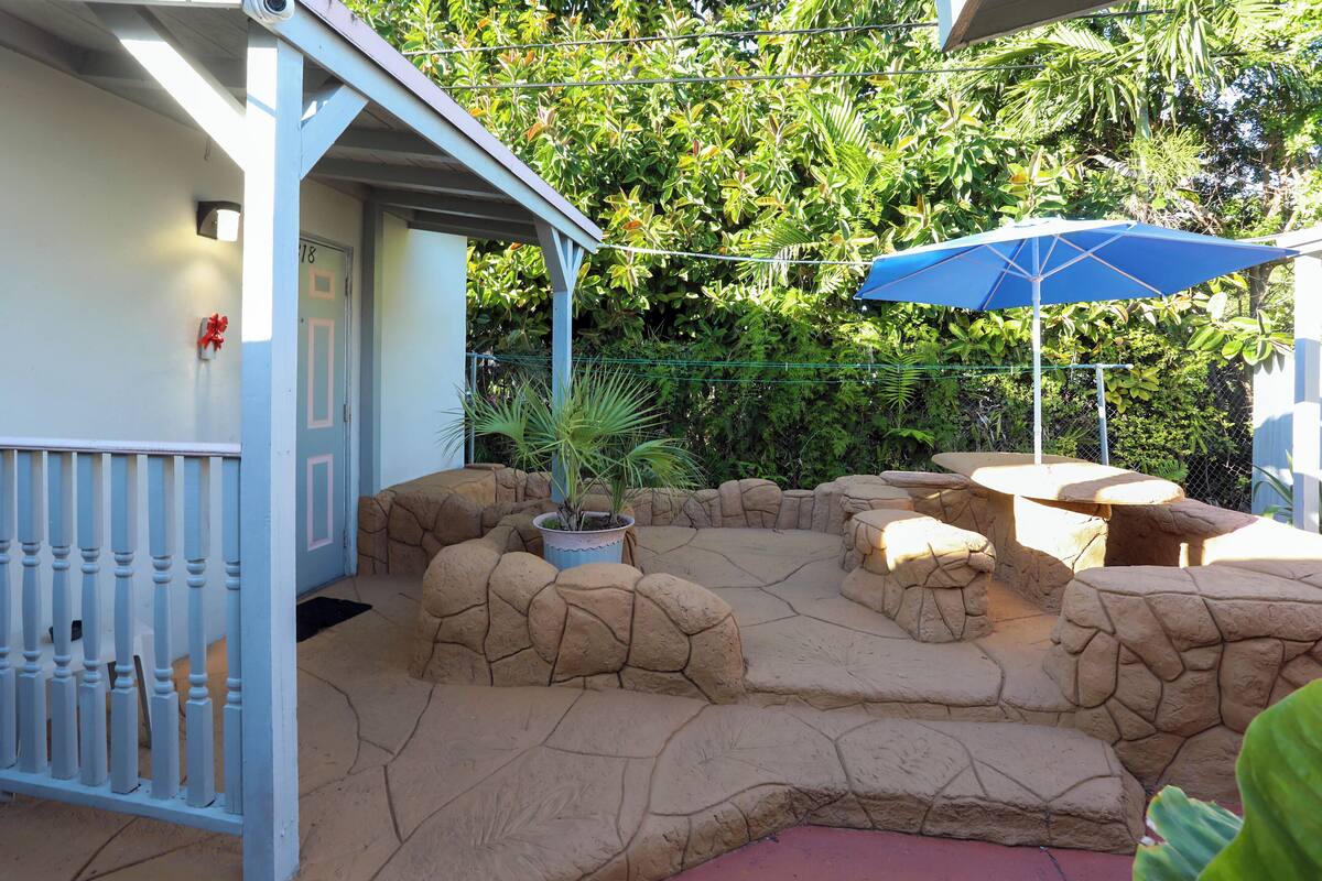 A patio area with a rock garden, a potted plant, and a table with an umbrella.