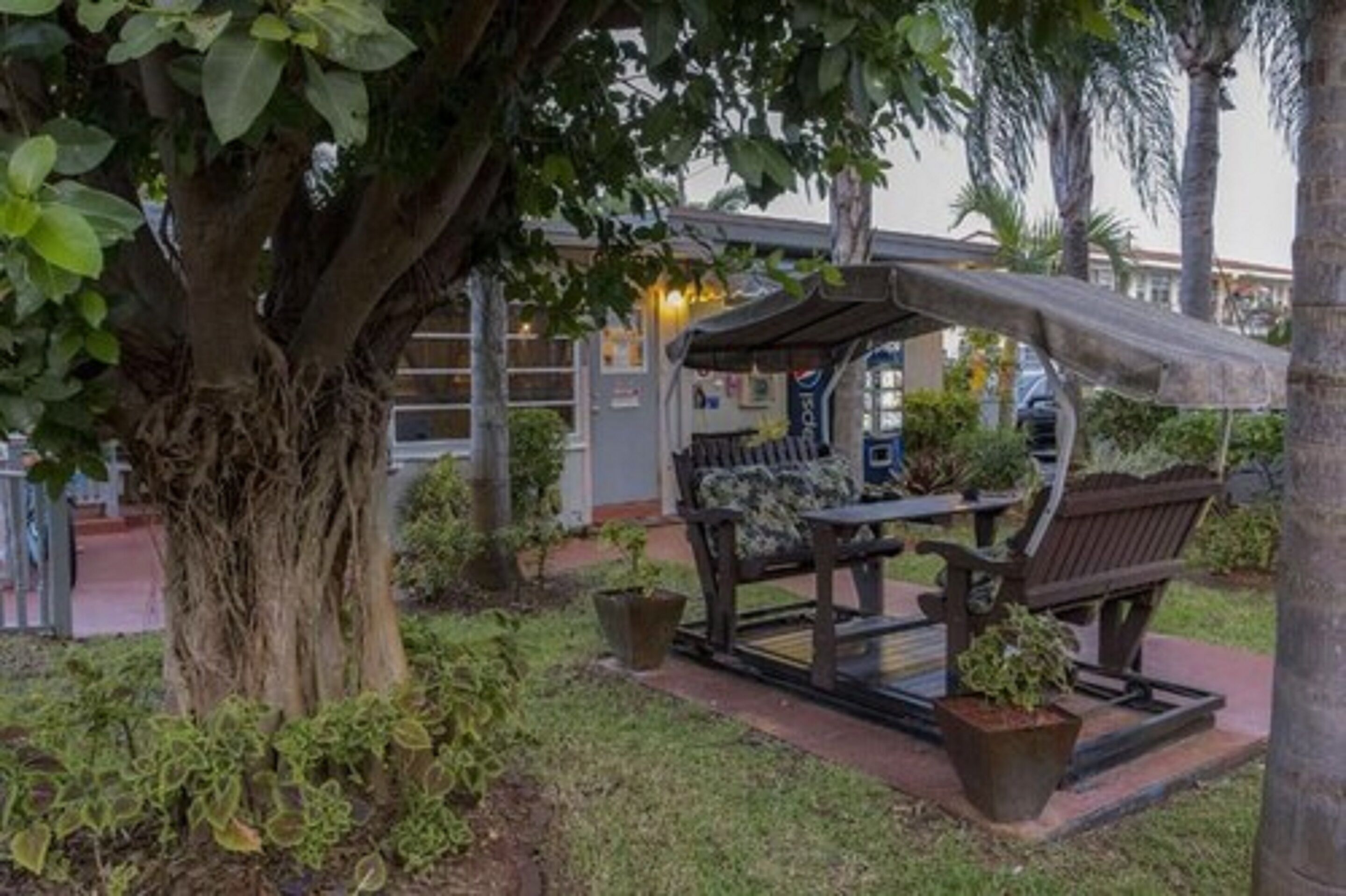 A covered outdoor seating area with a bench and potted plants.