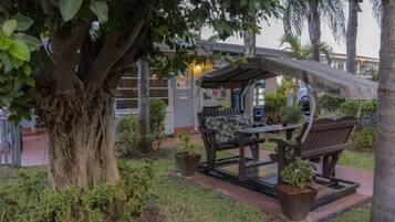 A covered outdoor seating area with a bench and potted plants.