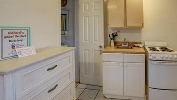 A kitchen with white cabinets, a stove, and a sink. There's a sign on the wall titled "Richard's Guest Services Directory".