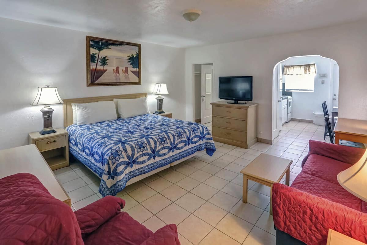 A hotel room with a bed, a TV, a desk, and a red sofa.