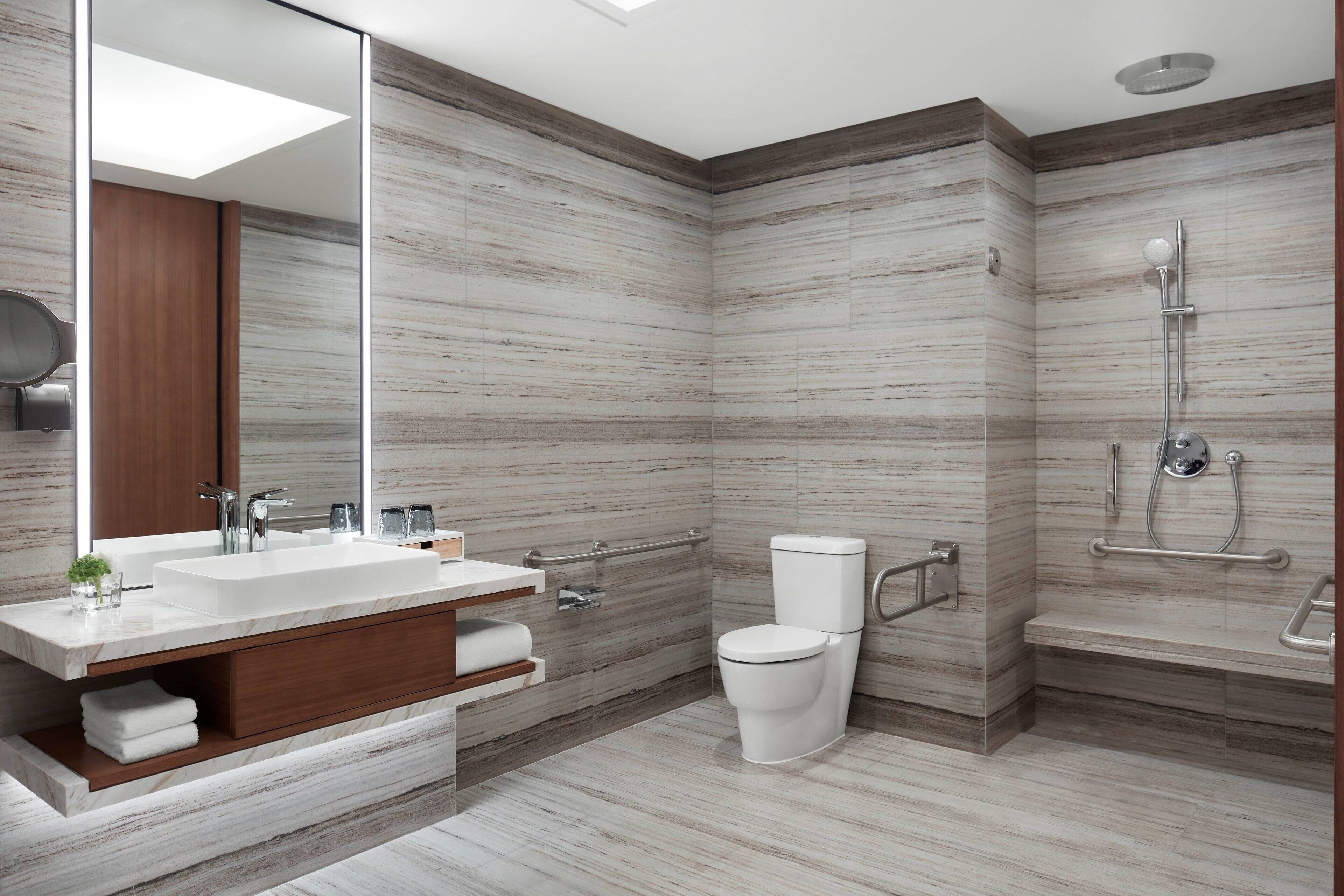 A modern bathroom with a large mirror, a sink, a toilet, and a shower area.