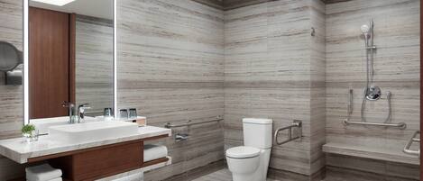 A modern bathroom with a large mirror, a sink, a toilet, and a shower area.