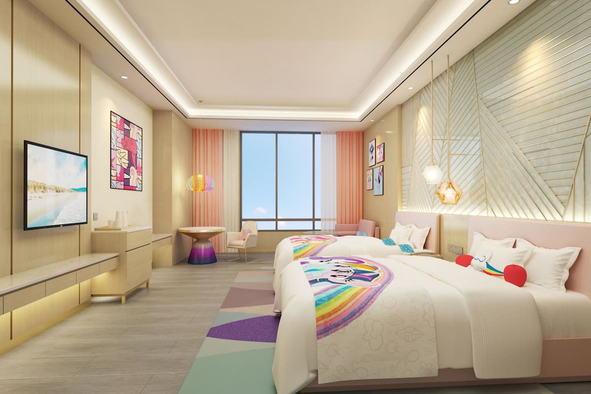 Une chambre d’hôtel moderne, dotée d’un grand lit, d’un bureau, d’une chaise et d’un téléviseur fixé au mur.